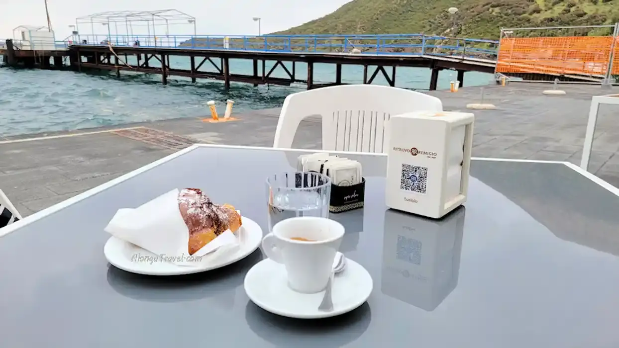a chocolate croissant & ☕ are served on my table overlooking the bay on Vulcano Aeolian Island for a sweet treat with a great view