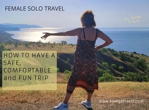 Alonga Travel the author stands on a hill in front of a sea & a sign: 'How to have a safe, comfortable and fun trip'