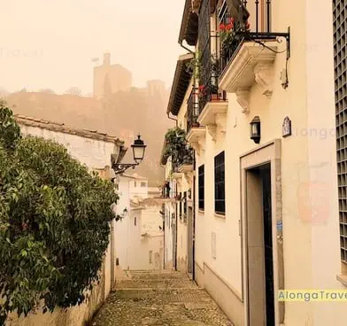 A narrow street with a view of Alhambra on a background during a solo trip to Spain