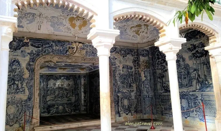A grotto with blue and white tiles in complicated pattern and latticework over a triple archway