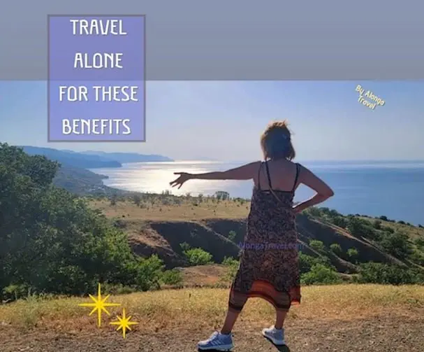 Alonga Travel the author standing on a cliff & a sign: 'Travel alone for these benefits'