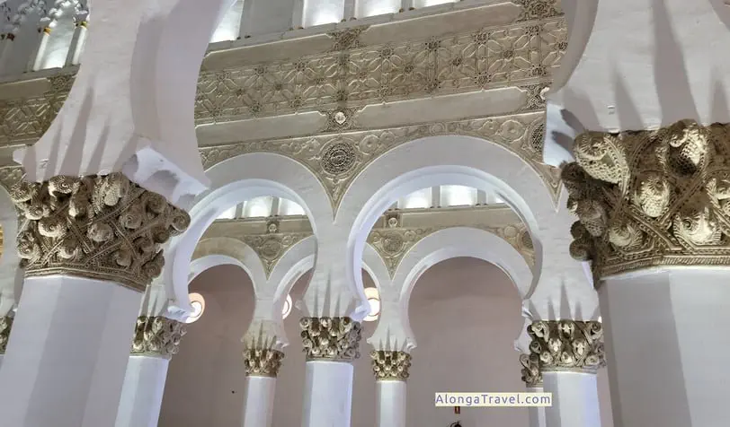 White horseshow arches and elaborate Jewish inscriptions and elements In a Mudejar style room