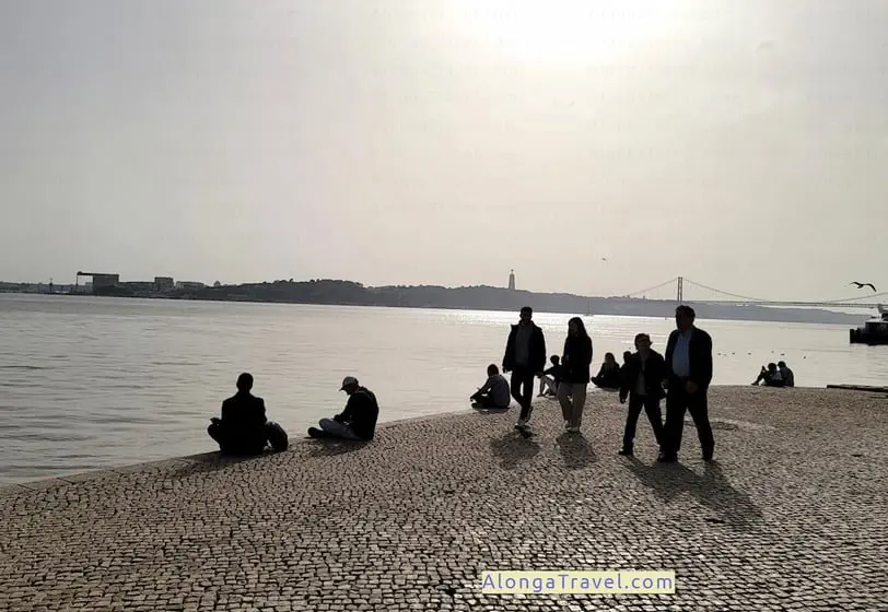 People sitting on a river waterfront enjoying sunshine