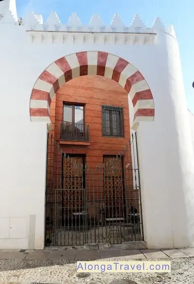 Horseshoe arched doorway of a building with white & pink bricks in Mudejar style