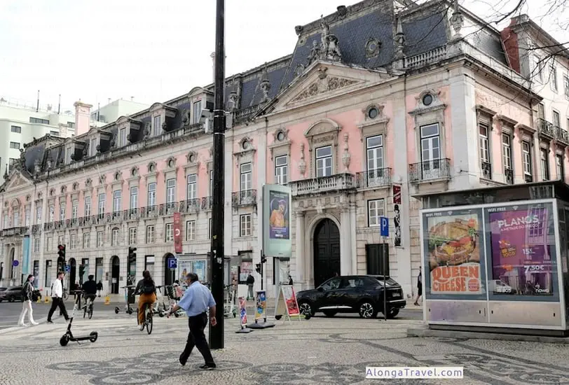 Ornate pink Pombaline style building with columns over the door and plastered decoration over window