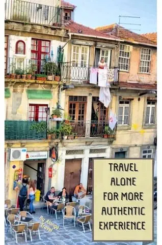 Sign: 'Travel alone for more authentic experiences' & table in a local café with local life around i