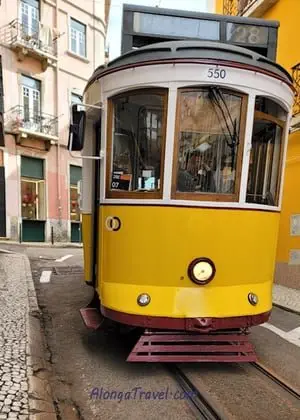 Iconic yellow narrow Tram 28 in Lisbon on a narrow lane.
