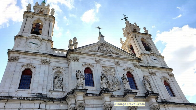 White facade of Estrela Basilica with many sculptures and bells