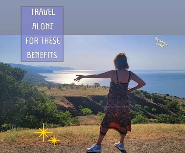 Alonga Travel the author standing on a cliff & a sign: 'Travel alone for these benefits'