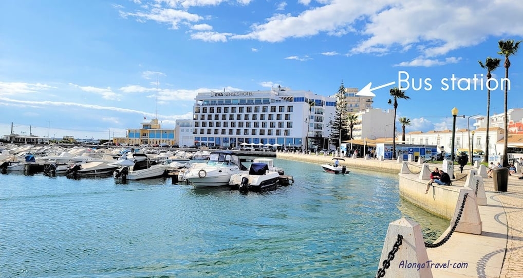 boats floating in Faro marina & a custom arrow pointing to a building marked 'bus station in Faro'