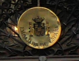 A golden emblem of Embajada de Espana with Spanish coats-of-armsh brown