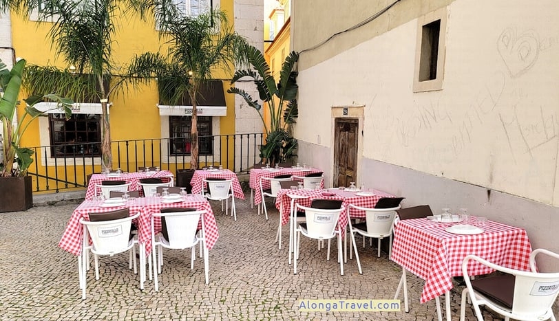 Colorful outdoor tables of a restaurant by Lisbon Cathedral wall