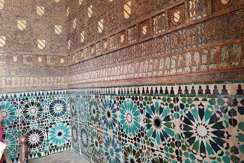 Colorfully decorated with tyles lower part of the wall, plus carved mudejar patterns on the upper wall